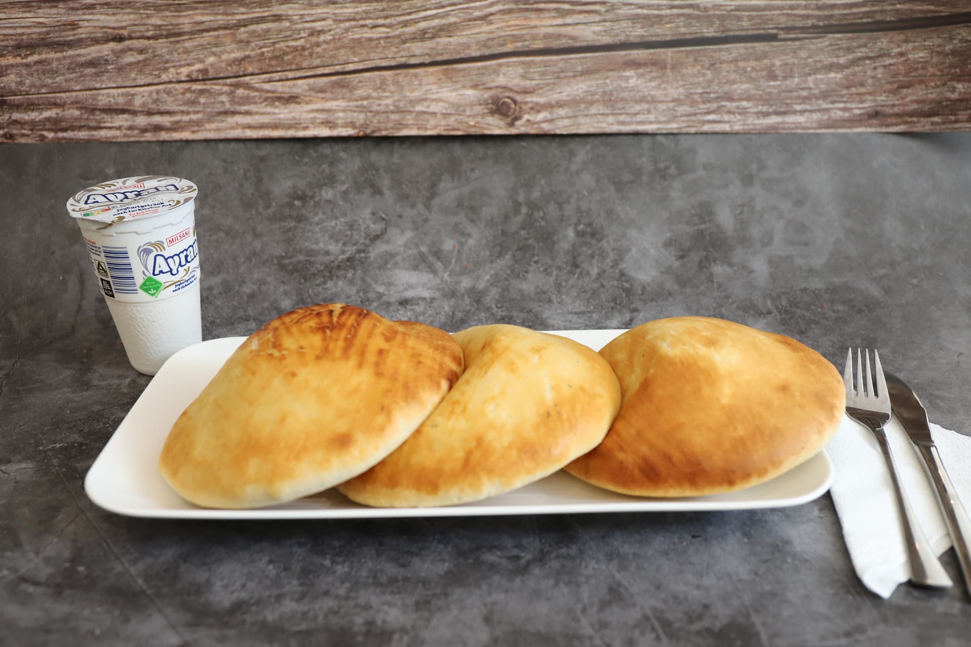 Drei frisch gebackene Pide auf einem Teller mit Ayran