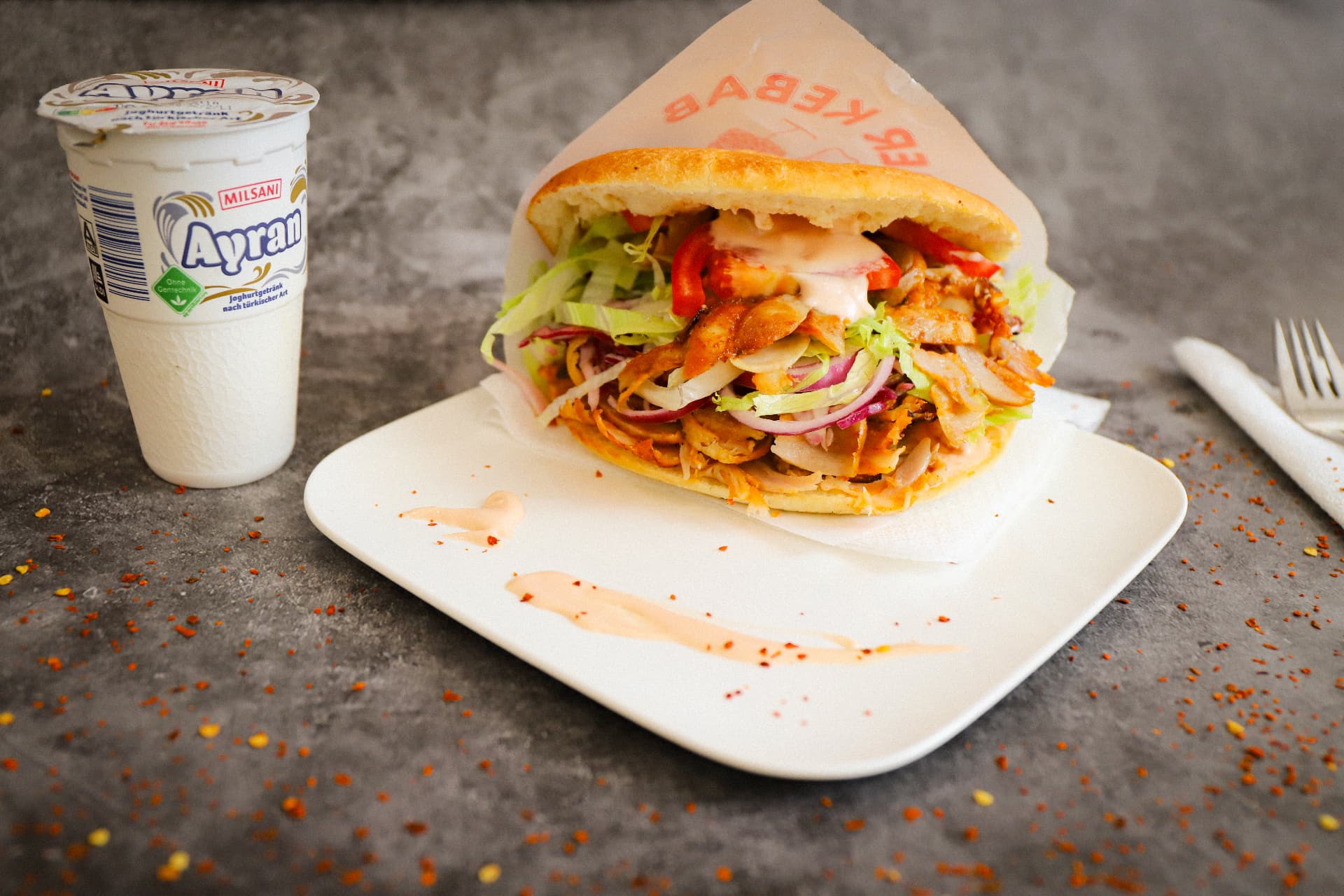 Döner im Fladenbrot mit Salat und Soße, dazu Ayran